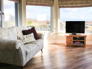a living room with a couch and a flat screen tv at Taigh Chailean in Lochs