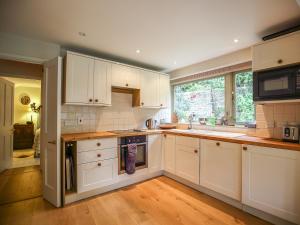 kuchnia z białymi szafkami, zlewem i kuchenką w obiekcie All Souls Cottage w mieście Cirencester