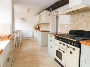 cocina con armarios blancos y fogones en Greenham Cottage, en Chiselborough