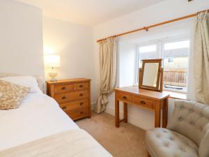 ein Schlafzimmer mit einem Bett, einem Spiegel und einem Stuhl in der Unterkunft Greenham Cottage in Chiselborough