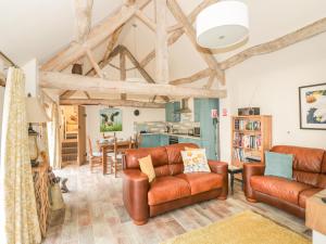 a living room with wooden ceilings and leather furniture at Megs Cottage in Alveston