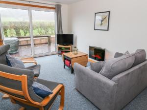 a living room with a couch and chairs and a tv at Kestrel Lodge in Beeswing