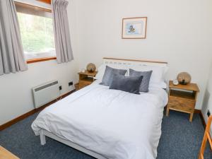 a bedroom with a white bed and a window at Kestrel Lodge in Beeswing