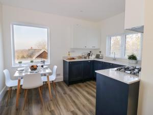 a kitchen with blue cabinets and a table with chairs at Chalk Cottage in Great Malvern