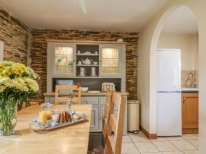 a kitchen with a table and a white refrigerator at Lily Cottage in Looe