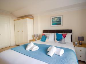 - une chambre dotée d'un grand lit avec des oreillers blancs et bleus dans l'établissement Harbourside Penthouse, à Weymouth
