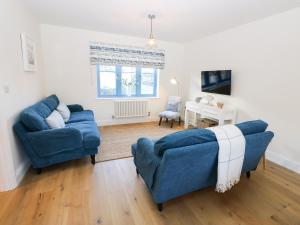 uma sala de estar com dois sofás azuis e uma secretária em Crab Cottage em Bembridge