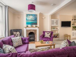 a living room with purple furniture and a fireplace at Wey Cottage in Weymouth