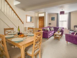 a living room with a wooden table and purple furniture at Wey Cottage in Weymouth