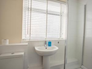 a white bathroom with a sink and a shower at Wey Cottage in Weymouth