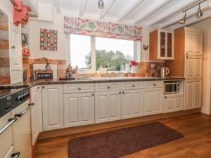 a kitchen with white cabinets and a large window at Rhianfa in Llanfairpwllgwyngyll