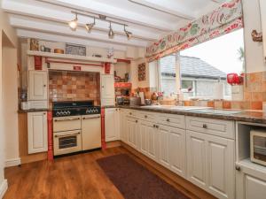 a kitchen with white cabinets and a large window at Rhianfa in Llanfairpwllgwyngyll