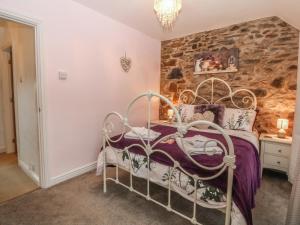 a bed in a room with a stone wall at Rhianfa in Llanfairpwllgwyngyll