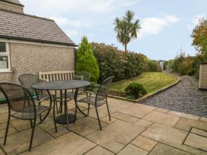 a patio with a table and chairs in a yard at Rhianfa in Llanfairpwllgwyngyll