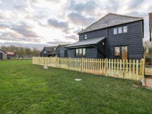 a black house with a wooden fence in a yard at The Granary in Halstead
