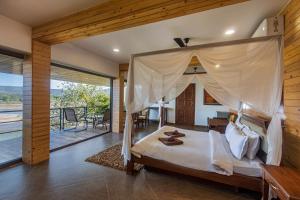 a bedroom with a canopy bed and a balcony at SaffronStays Athaang, Dapoli in Ānjarle +104 photos