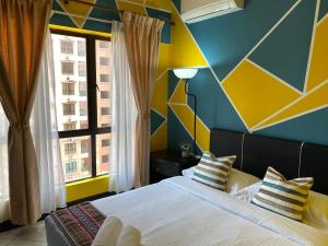 1 dormitorio con 1 cama con pared amarilla y azul en JJ Homes Marina Court, en Kota Kinabalu