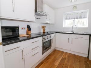 eine Küche mit weißen Schränken und schwarzen Arbeitsplatten in der Unterkunft The Duck House in Norwich