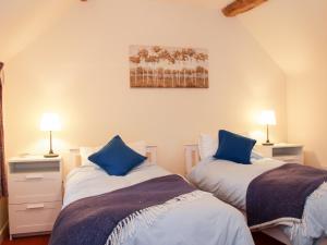 two beds in a room with blue pillows at Cream Door Cottage in Kidderminster