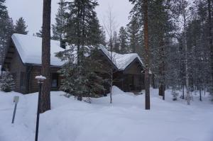 eine Blockhütte mit Schnee auf dem Dach im Wald in der Unterkunft Kantokelo B2 in Ylläsjärvi