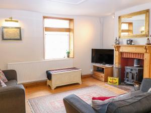 a living room with a fireplace and a tv at 3 Station Cottages in Wymondham