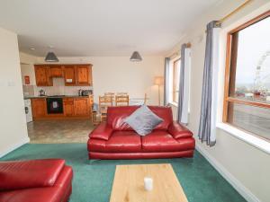 uma sala de estar com um sofá de couro vermelho e uma mesa em Apartment 42 em Bundoran