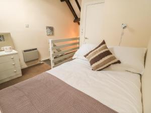 a bedroom with a white bed with a pillow on it at Wren Cottage in Morpeth