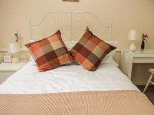 a white bed with two pillows on top of it at Heron Cottage in Morpeth