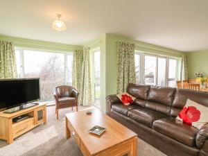a living room with a leather couch and a tv at Tamar 4 in Callington
