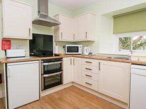 a kitchen with white cabinets and a sink at Cairnhill in Girvan