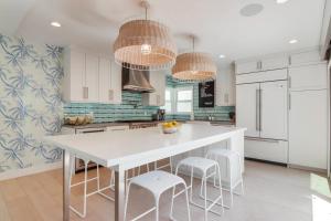 a kitchen with white cabinets and a white table and stools at Brighton Dream in San Diego