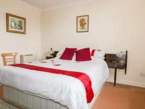 een slaapkamer met een groot wit bed met rode kussens bij Yellow Sands Apartment 5 in Padstow