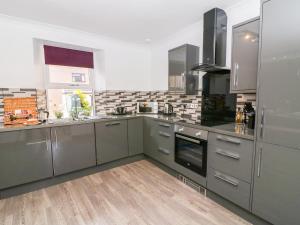 a kitchen with stainless steel appliances and gray cabinets at 2 Station View in Long Marton