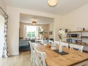 a dining room and living room with a wooden table and chairs at Bryn Dale in Trearddur