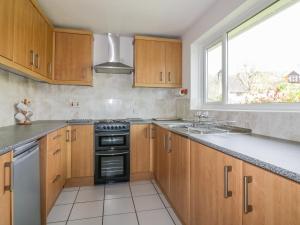 a kitchen with wooden cabinets and a stove and a window at Brambles in Gorran Haven