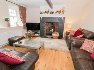 a living room with leather couches and a fireplace at Hafodty in Conwy