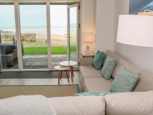 a living room with a couch and a view of the beach at Chapel Rock View, The Dunes in Perranporth