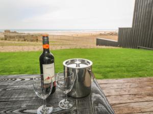 a bottle of wine and two wine glasses on a table at Chapel Rock View, The Dunes in Perranporth