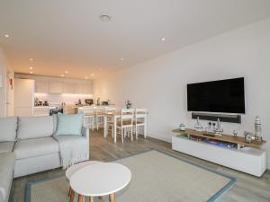 a living room with a couch and a flat screen tv at Chapel Rock View, The Dunes in Perranporth