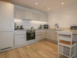 a kitchen with white cabinets and a table and a chair at Chapel Rock View, The Dunes in Perranporth
