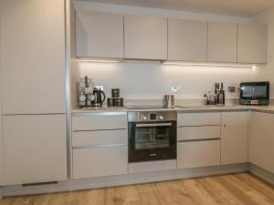 a kitchen with white cabinets and a microwave at Chapel Rock View, The Dunes in Perranporth