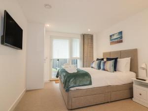 a bedroom with a large bed with a flat screen tv at Chapel Rock View, The Dunes in Perranporth
