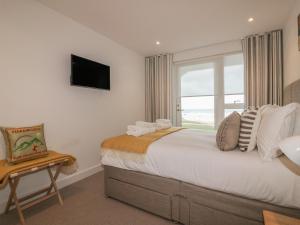a bedroom with a large bed with a window at Chapel Rock View, The Dunes in Perranporth