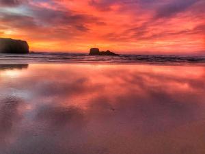 a sunset on a beach with a cloudy sky at Chapel Rock View, The Dunes in Perranporth