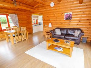 Beech Lodge في أوكهام: غرفة معيشة مع أريكة جلدية وطاولة