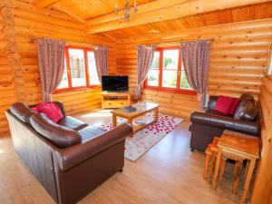 a living room with couches and a tv in a log cabin at Sycamore Lodge in Oakham