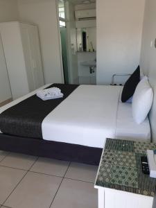 a bedroom with a large white bed and a table at Original North Australian in Bowen