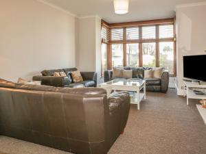 a living room with a leather couch and a tv at Chy-an-Brae in Newquay