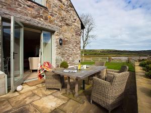 - une table et des chaises sur la terrasse d'une maison dans l'établissement Estuary Cottage, à Penrhos-Lligwy