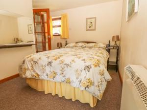 a bedroom with a bed with a floral bedspread at Cordwainer Cottage in Stoke on Trent